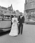 880986 Portret van het bruidspaar Bouman-Zwart, bij een klassieke automobiel voor het Stadhuis (Stadhuisbrug 1) te ...